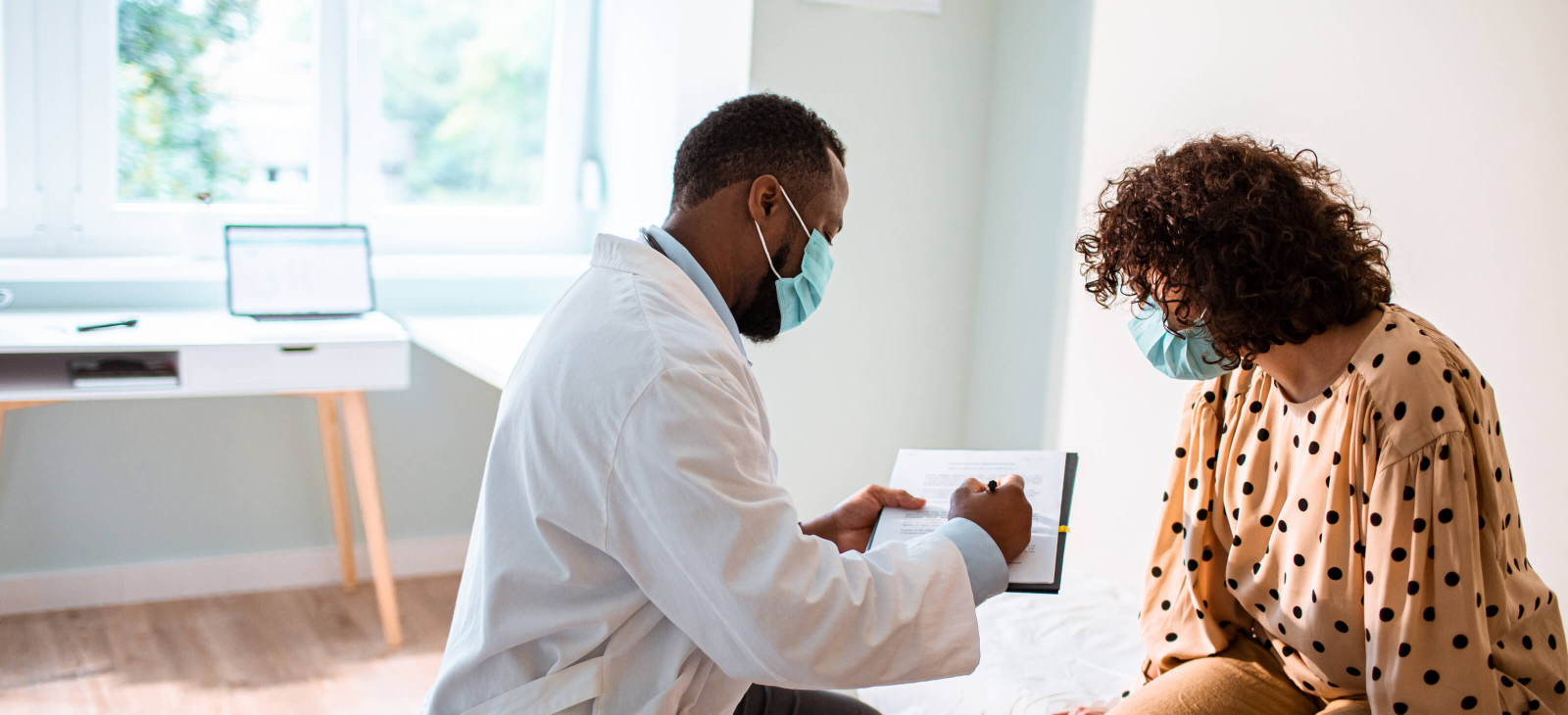 Full-width - Clinician Man Talking Patient Woman Masks